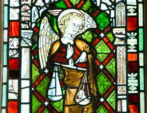 Stained glass figure of St Michael weighing souls