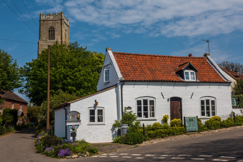 A whitewashed cottage and church tower in Happisburgh