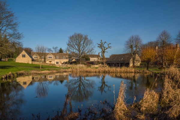 Westwell village pond and Cotswold stone cottages