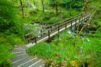 The path drops down to a narrow footbridge across the River Kinglas