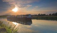 A narrowboat glides down the river at sunset