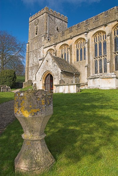A fanciful urn stands in the churchyard. Photo of St Andrew's Church, Chedworth, Gloucestershire.