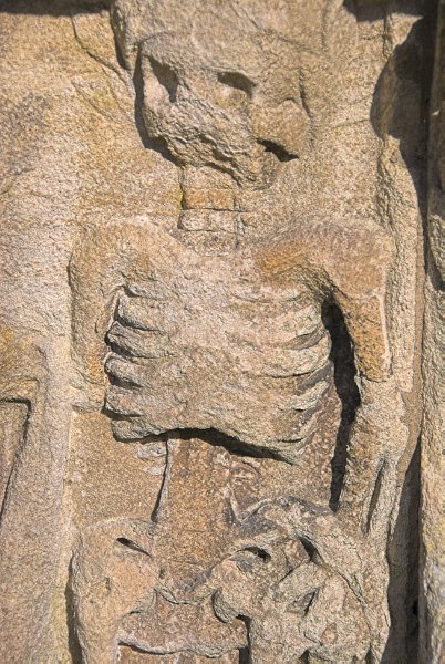 A delightfully gruesome skeleton carved on a table tomb in the churchyard. Photo of St Andrew's Church, Chedworth, Gloucestershire.