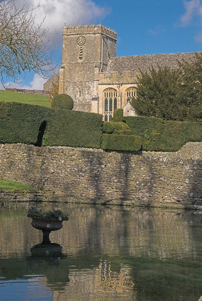 The view of St Andrew's across a small ornamental pool in the grounds of Chedworth Manor. Photo of St Andrew's Church, Chedworth, Gloucestershire.