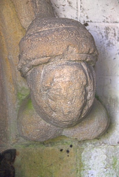 This is the westernmost carved head on the north door.  It is too weathered to see the features clearly. Photo of St Oswald's Church, Compton Abdale, Gloucestershire.