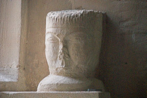 A 12th century carved head sits upon a window ledge on the south wall. The carving may have been intended as a corbel head. Photo of St Peter's Church, Little Barrington, Gloucestershire. Part of the Britain Express historic picture library.