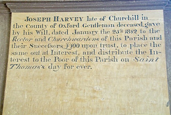 This memorial tablet to local benefactor Joseph Harvey (d. 1812) is set upon the west wall of the nave. Harvey was a resident of Churchill who left 100 pounds, the interest on which was to be distributed to the poor of Oddington on St Thomas's Day. Photo of St Nicholas' Church, Lower Oddington, Gloucestershire. Part of the Britain Express historic picture library.