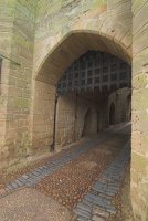 An old portcullis hangs above the gatehouse entrance