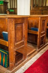 A sliding apprentice seat on a pew