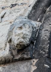 A worn carved head on the gateway exterior