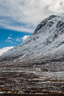A lonely dwelling cowers beaneath a snowy peak