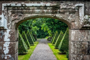 Topiary avenue seen through a gateway arch