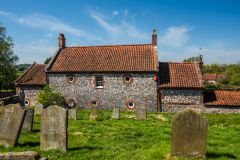 A brick and flint cottage by the churchyard