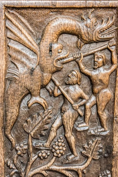 16th-century bench end of naked men fighting a dragon
