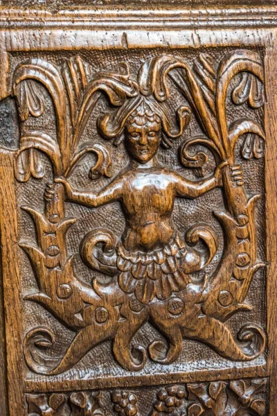 A twin-tailed mermaid bench end, c. 1534