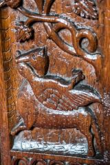 Bench end of a fox carrying a goose