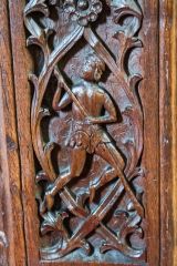 Bench end of a man vaulting over a rhyne (ditch)