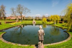A peaceful pond with the manor house beyond