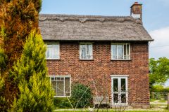 A thatched brick house opposite the Norfolk Wildlife Trust Visitor Centre