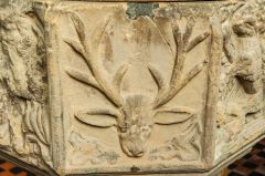 Carving of a stag's head on the font