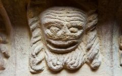 Grotesque carved head on the font
