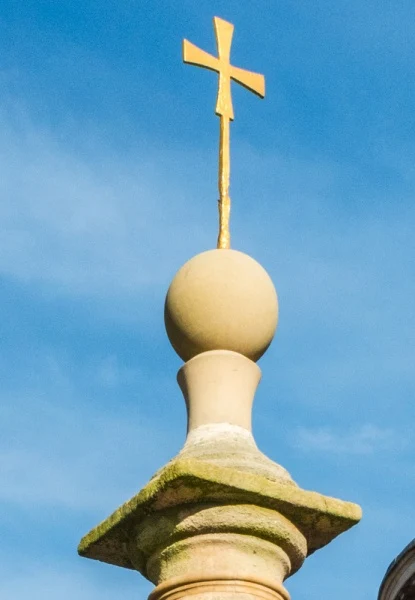 The gilded cross and ball atop the column
