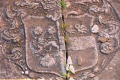 A worn coat of arms on a grave slab
