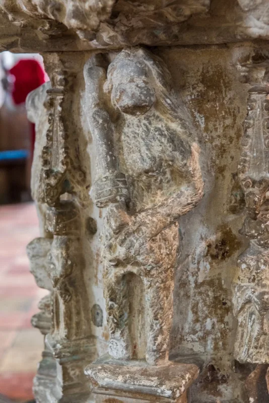 Carving of a female woodwose on the font stem