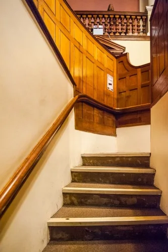 Climb the stairs to the prisoner's dock in the courtroom