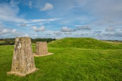 An OS trig marker and panorama stone stand at the centre of the hillfort