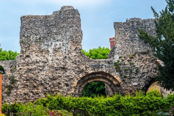 Ruined arches just visible through hedges