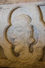 A carved head on the font