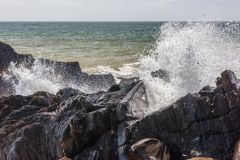 Waves crash on the shore beside the cave