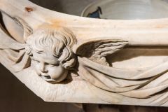 A carved cherub on the font bowl