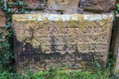 Ruined gravestone built into the nave wall
