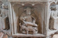 A defaced carved figure on the font bowl