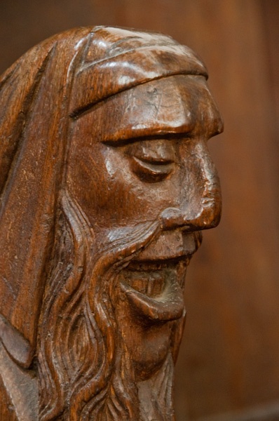Carved head bench end on a choir stall