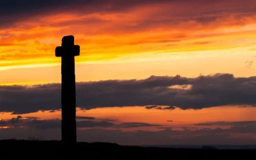 The cross silhouetted against the setting sun