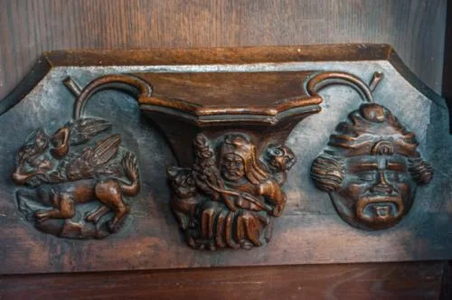 Misericord of an old woman with a distaff. On the left is a fox carrying away a fowl