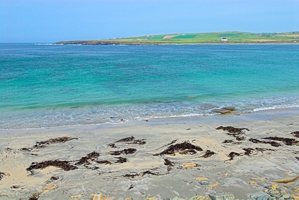 Looking out on the turquoise waters of Skaill Bay from the Skara Brae prehistoric village. Photo of the Orkney Islands, Scotland.