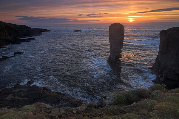 The sun setting beyond Castle Rock, a lovely old sea stack with a hole right through the centre. Photo taken at Yesnaby, Orkney Islands, Scotland.