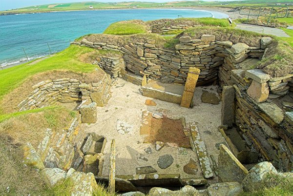 Another view of the same hut, showing the Bay of Skaill beyond. The hut is well-provided with storage containers. Photo of Skara Brae, a prehistoric village on the Orkney Islands, Scotland.