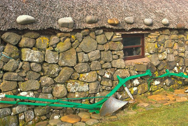 A plough leans against a stone cottage at the Museum of Island Life, Kilmuir on the Isle of Skye, Scotland. Part of the Britain Express Travel Guide to the Isle of Skye.