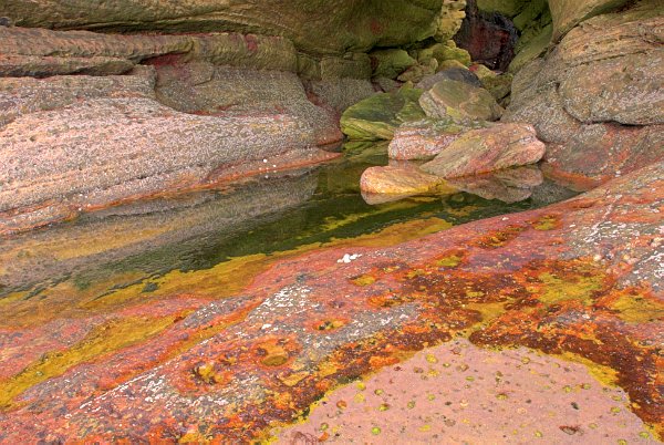 A tide pool reflects the pink rock formations at Prince Charlie's Cave. Stock photo of Prince Charlie's Cave on the Isle of Skye, Scotland. Part of the Britain Express Travel and Heritage Picture Library, Scotland collection.