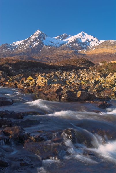 View of the snowcapped Cuillin Hills from the rocky shores of the Sligachan River. Stock photo of the Isle of Skye, Scotland. Part of the Britain Express Travel and Heritage Picture Library, Scotland collection.