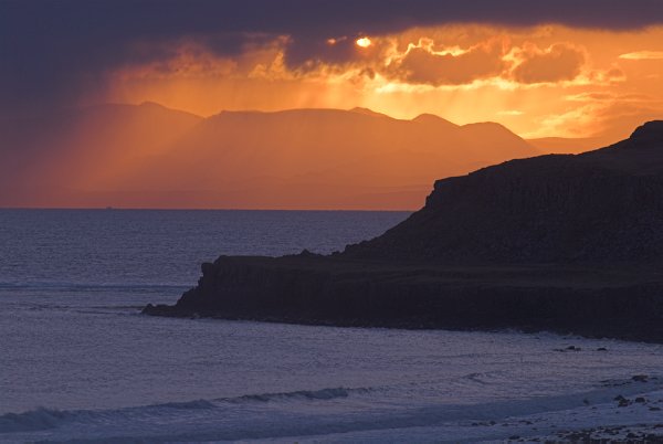 Sunrise glows beyond storm clouds at Staffin. Stock photo of the coast at Staffin on the Isle of Skye, Scotland. Part of the Britain Express Travel and Heritage Picture Library, Scotland collection.