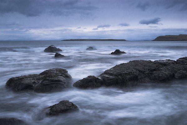 An almost monochrome picture of nightfall on the rock strewn shore at Staffin, on the Trotternish peninsula. Stock photo of the coast at Staffin on the Isle of Skye, Scotland. Part of the Britain Express Travel and Heritage Picture Library, Scotland collection.