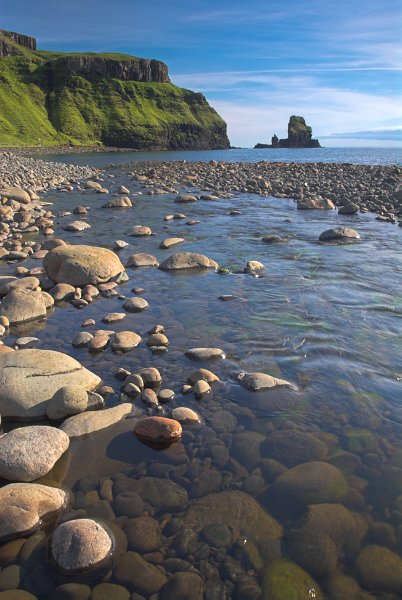 Photo of the clear water of Talisker Bay. The sea stack in the distance is tiny compared to the cliffs. Stock photo of the coast at Talisker on the Isle of Skye, Scotland. Part of the Britain Express Travel and Heritage Picture Library, Scotland collection.