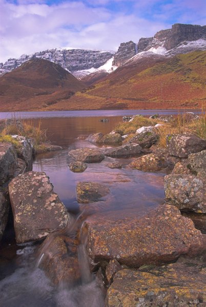 The Trotternish escarpment with a small loch in the foreground. Photo taken from a slightly different angle from the previous picture and with warmer light. Stock photo of the Trotternish Ridge near Staffin on the Isle of Skye, Scotland. Part of the Britain Express Travel and Heritage Picture Library, Scotland collection.